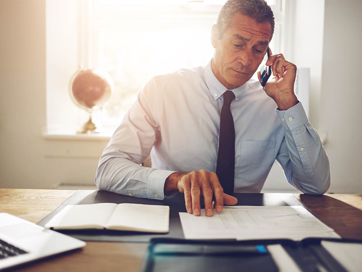 businessman sitting at desk while talking on smartphone