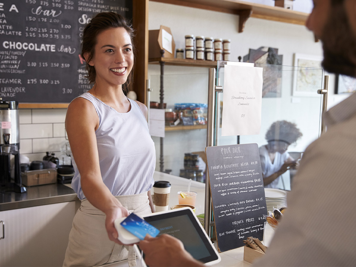 Customer at coffee shop pays smiling waitress with card